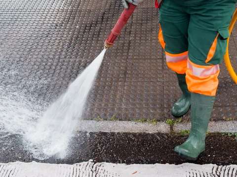 Worker power washing sidewalk