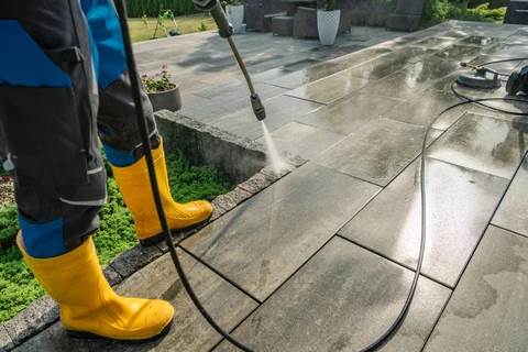 Worker cleaning stone patio with pressure washer